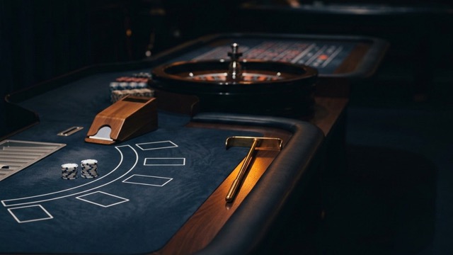 A live-casino table laid out for play with a roulette wheel in the background